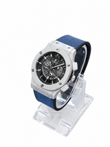 Men's silver skeleton chronograph watch with blue leather-style strap, black open-style dial and silver-tone case