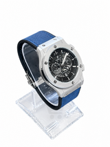 Men's silver skeleton chronograph watch with blue leather-style strap, black open-style dial and silver-tone case